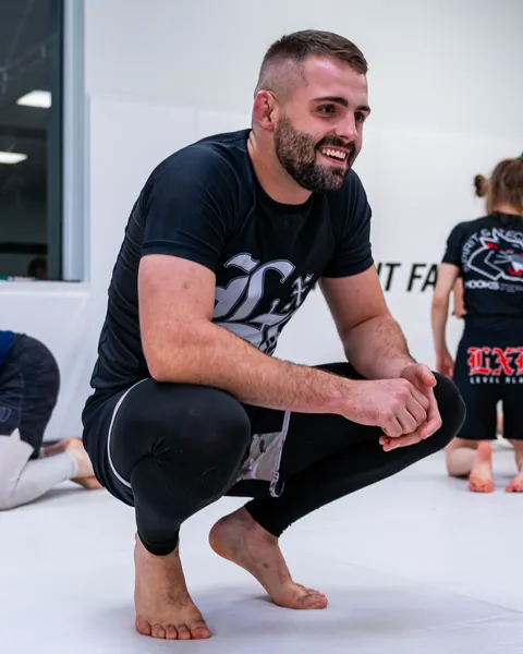 William Tackett smiling while watching training on the mat.